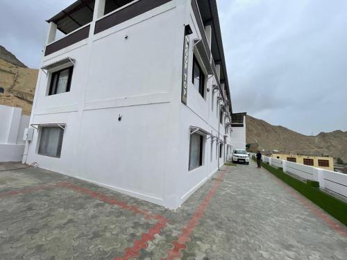 a white building with a red line in front of it at Roof Top Homestay in Leh