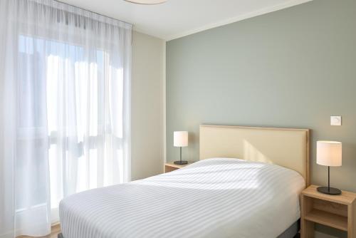 une chambre blanche avec un lit et une fenêtre dans l'établissement Zenitude Hôtel-Résidences Chambéry, à Chambéry