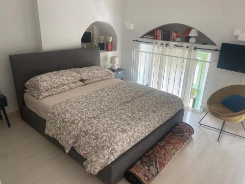 une chambre avec un grand lit et une chaise dans l'établissement Mentone, appartamento a 80 mt dal mare, à Menton