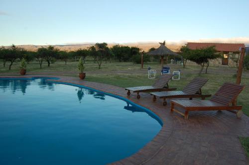 a swimming pool with two lounge chairs next to it at Alto Valle Cabañas de Montaña in Mina Clavero
