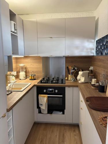 La cuisine est équipée de placards blancs et d'un four avec plaques de cuisson noires. dans l'établissement Appart modernise vue mer ambiance Marine, à Saint Cyprien Plage