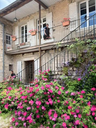 a man standing on the balcony of a house with pink flowers at Castel Rochefort sur Nenon Jura in Rochefort-sur-Nenon