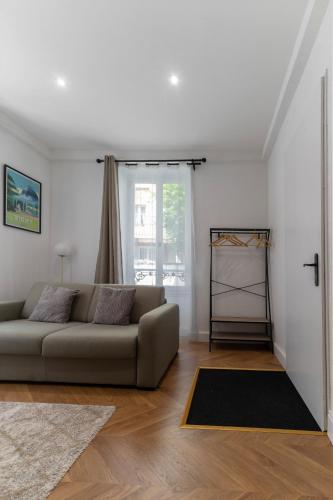 a living room with a couch and a window at Chez Juliette Triangle d'Or - Rez de Chaussée in Vichy