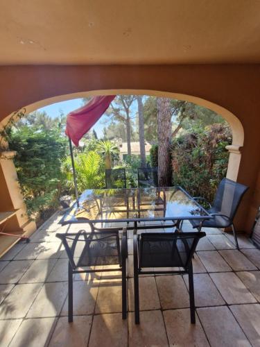 une table et des chaises sur une terrasse avec une fenêtre dans l'établissement Cavalaire sur mer maison de vacances, à Cavalaire-sur-Mer