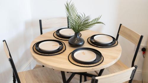 a wooden table with plates and a vase on it at Luxury 1-bed Near MCR Hospital & City Centre in Manchester