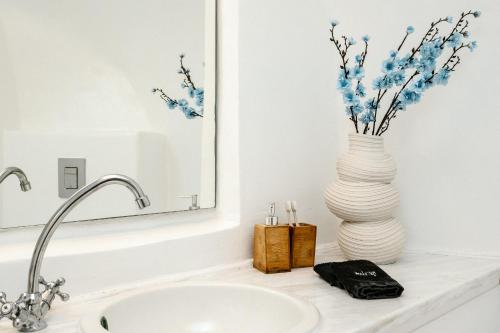 a bathroom with a sink and a vase with flowers at Nano Oia Canaves in Oia