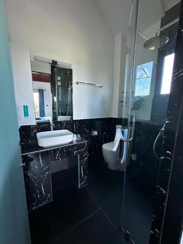 a bathroom with a sink and a toilet and a shower at Lucky Monkey Inn and Restaurant in Weligama