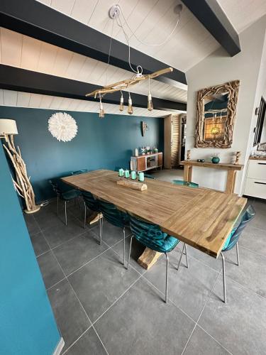 une salle à manger avec une table en bois et des murs bleus dans l'établissement Villa les Dunes les pieds dans le sable SPA 5ch, au Bois-Plage-en-Ré