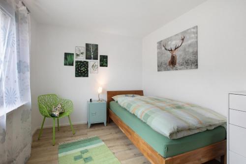 a bedroom with a bed and a green chair at Haus Petra in Kandern