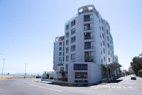 a tall white building on the side of a street at Ocean Breeze Hotel in Strand