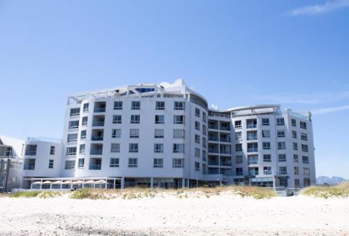 a white building on the beach next to the sand at Ocean Breeze Hotel in Strand