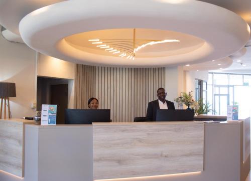 two people sitting at a reception desk with laptops at Ocean Breeze Hotel in Strand