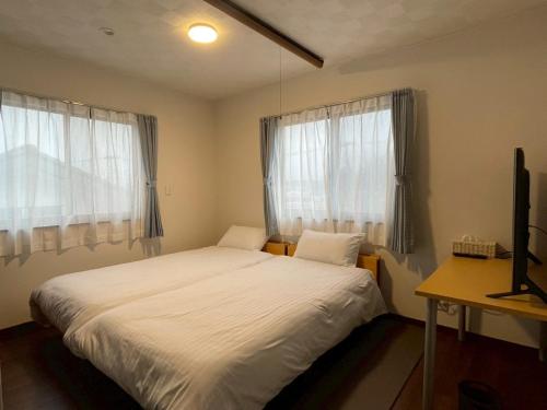 a bedroom with a white bed and two windows at 河口湖駅徒歩10分 ベルショッピングセンター徒歩6分 大型4ldk屋根裏付き 全室空調 in Wada