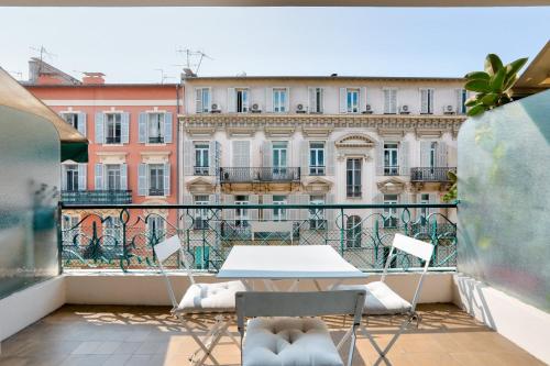 - un balcon avec une table, des chaises et des bâtiments dans l'établissement GuestReady - Cosy stay with Terrace in Carré d'Or, à Nice