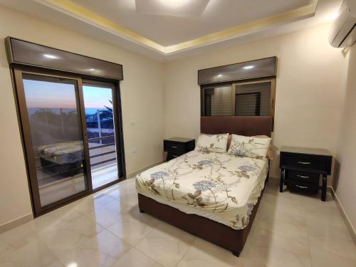 a bedroom with a bed and a large window at Janna2Villa in Tall al Misţāḩ