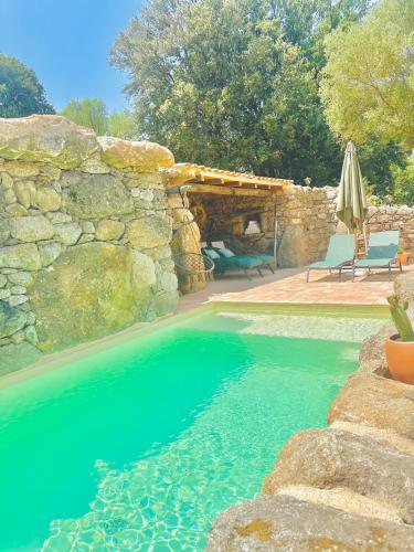 - une piscine avec un mur en pierre et de l'eau bleue dans l'établissement La Casa D'Ange Bergerie de Luxe Piscine chauffée, à Lama