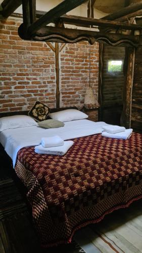 a large bed in a room with a brick wall at La Colibe, cătun arhaic ecologic in Constanţa