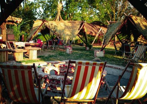 two lawn chairs and a table in a yard with umbrellas at La Colibe, cătun arhaic ecologic in Constanţa