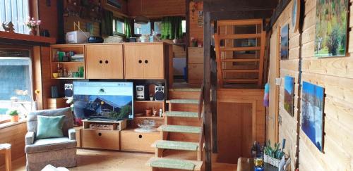 a room with a staircase and a television in a house at Ferienhaus Bernau13, Rechbergblick in Bernau im Schwarzwald