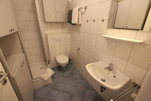 une salle de bain blanche avec toilettes et lavabo dans l'établissement Rasmus 29, à Langeoog