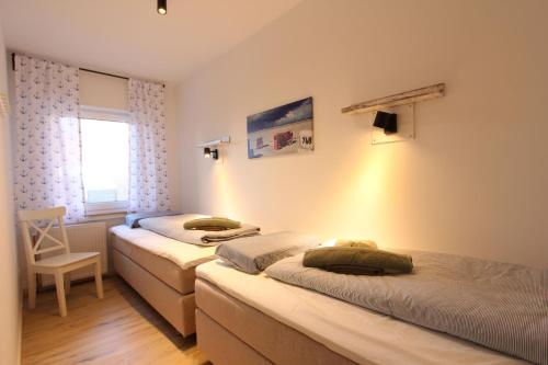 two beds in a room with a window at Strandliebe in Langeoog