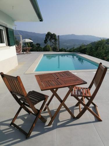 a table and two chairs next to a swimming pool at Central Suites Arouca in Arouca