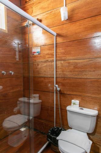 a bathroom with a toilet and a glass shower at Pousada Cabanas Paraiso in Ilha Grande