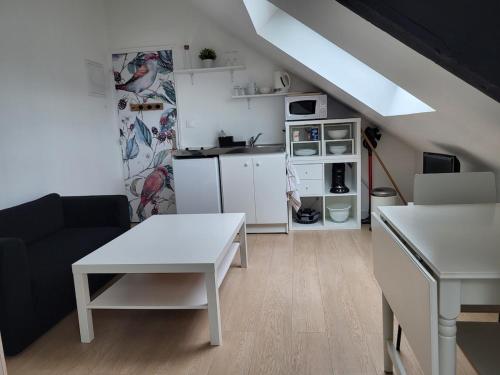 Il comprend un salon avec une table blanche et une cuisine. dans l'établissement Cocon sous les toits, à Dinan