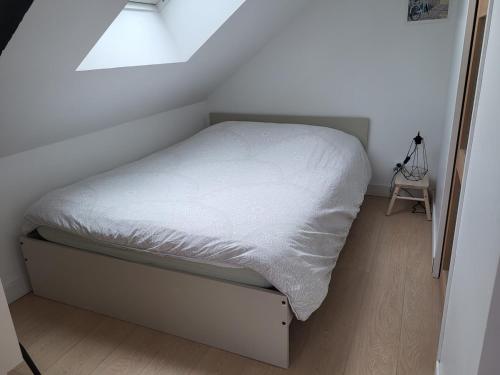- un petit lit dans une petite chambre avec fenêtre dans l'établissement Cocon sous les toits, à Dinan