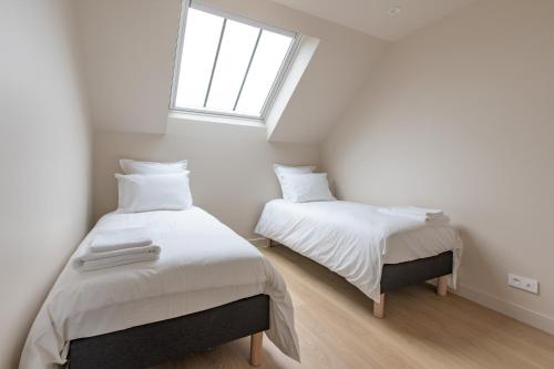two beds in a white room with a window at Les Clavendiers - Le Refuge in Nuits-Saint-Georges