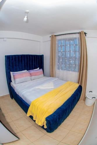 ein Schlafzimmer mit einem großen Bett und einer gelben Decke in der Unterkunft Hamptons Homes Stylish 1 Bedroom Stay close to Eldoret Town in Eldoret