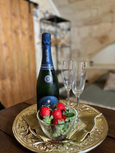 a bottle of wine and a bowl of strawberries on a gold plate at la nicchia, relax room & salento stay in Manduria