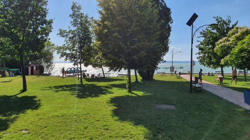 a park with trees and people on the beach at Holiday home in Balatonvilagos 31292 in Balatonvilágos