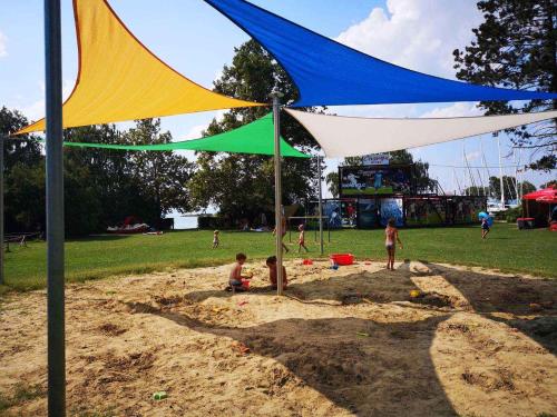 a group of children playing in the sand under a tent at Holiday home in Balatonvilagos 31292 in Balatonvilágos