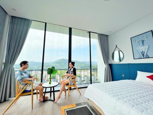 a man and woman sitting in chairs in a bedroom at FLAMINGOS Villa Happy 3 phòng ngủ- view Hồ- bể bơi riêng in Ngọc Quang