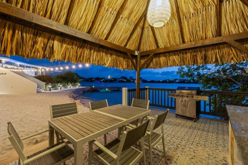 a table and chairs under a straw umbrella on a beach at Dolce Vita Beach, Waterfront Bungalows with Private Beach in Willemstad
