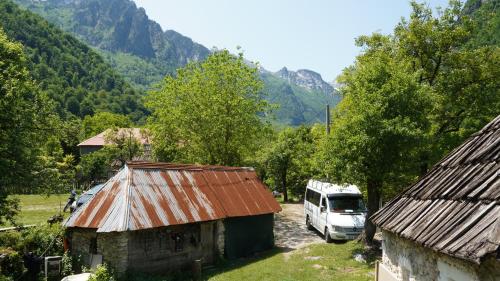 a van parked next to a building with mountains in the background at Motina River Guesthouse in Tropojë