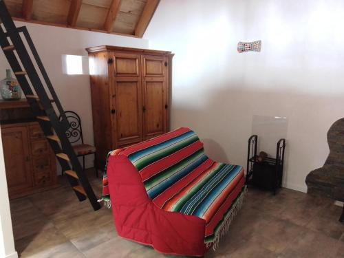 - un salon avec une chaise rouge et un escalier dans l'établissement La Loge de Fleur, à Anglars-Saint-Félix