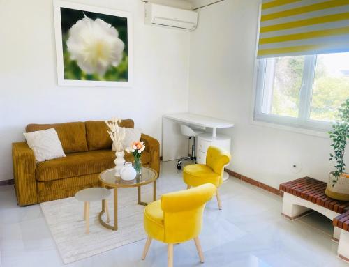 - un salon avec un canapé, une table et des chaises jaunes dans l'établissement Maison indépendante 52 m2, clim, wifi et jardin, à La Londe-les-Maures