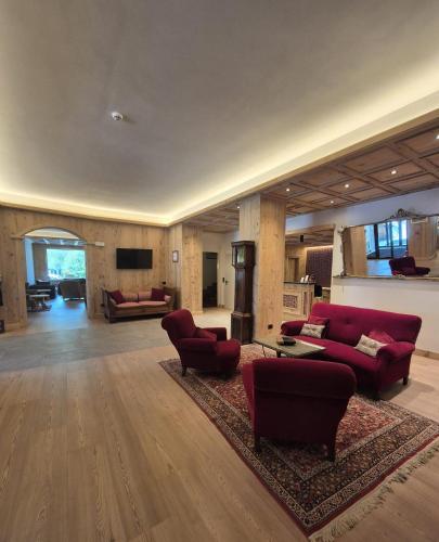 a large living room with red couches and chairs at Hotel Baita Dei Pini in Bormio