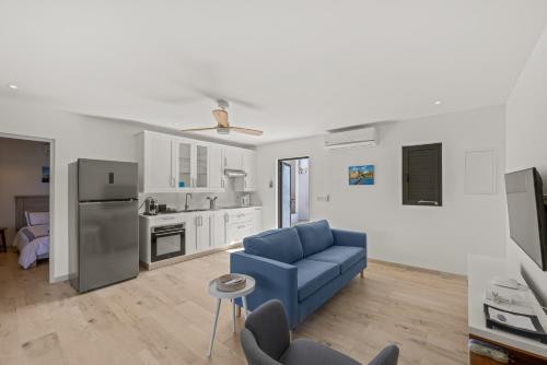 a living room with a blue couch and a kitchen at Dolce Vita Beach, Waterfront Bungalows with Private Beach in Willemstad