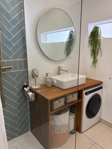 une salle de bain avec un lavabo et un miroir et une machine à laver dans l'établissement Vue mer et port 6eme etage Magnifique !, à Saint Cyprien Plage
