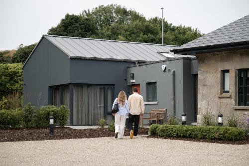 a man and woman walking in front of a house at Roe Valley Resort in Limavady