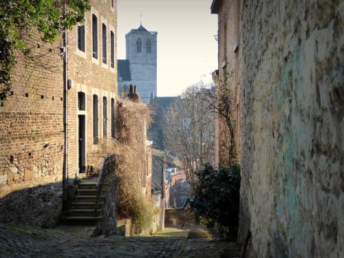 an alley in an old building with a tower in the background at La renaissance in Villers-lʼÉvêque
