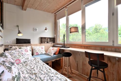a bedroom with a bed and a desk and windows at Cabane Petit Bouddha in Arrien-en-Bethmale