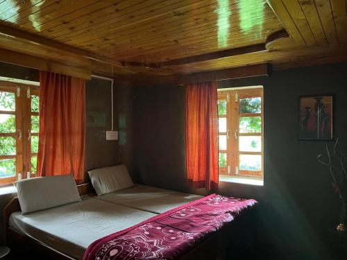 a bed sitting in a room with two windows at The Nest Farm Stay in Karsog in Karsog