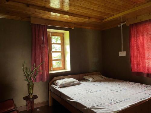 a bedroom with a bed with a red window at The Nest Farm Stay in Karsog in Karsog