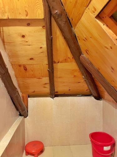a bathroom with wooden ceilings and a red stool at The Nest Farm Stay in Karsog in Karsog