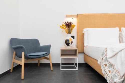 a bedroom with a bed and a chair and a vase with flowers at NG Guest House il Gallura in Olbia