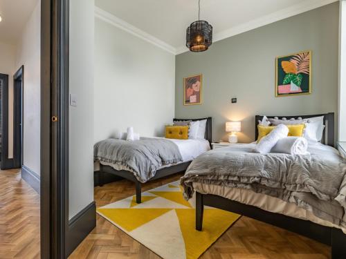 a bedroom with two beds and a yellow rug at 5 Bed in Westward Ho 78690 in Bideford